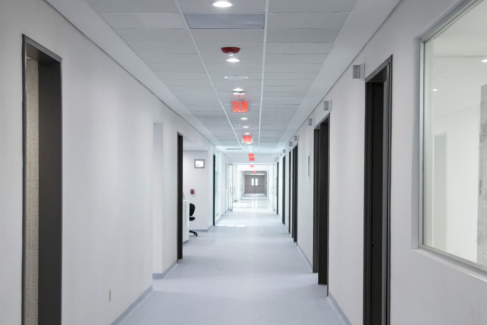 Brightly lit clinical corridor with clearly marked exit signage. Contextual healthcare photography.